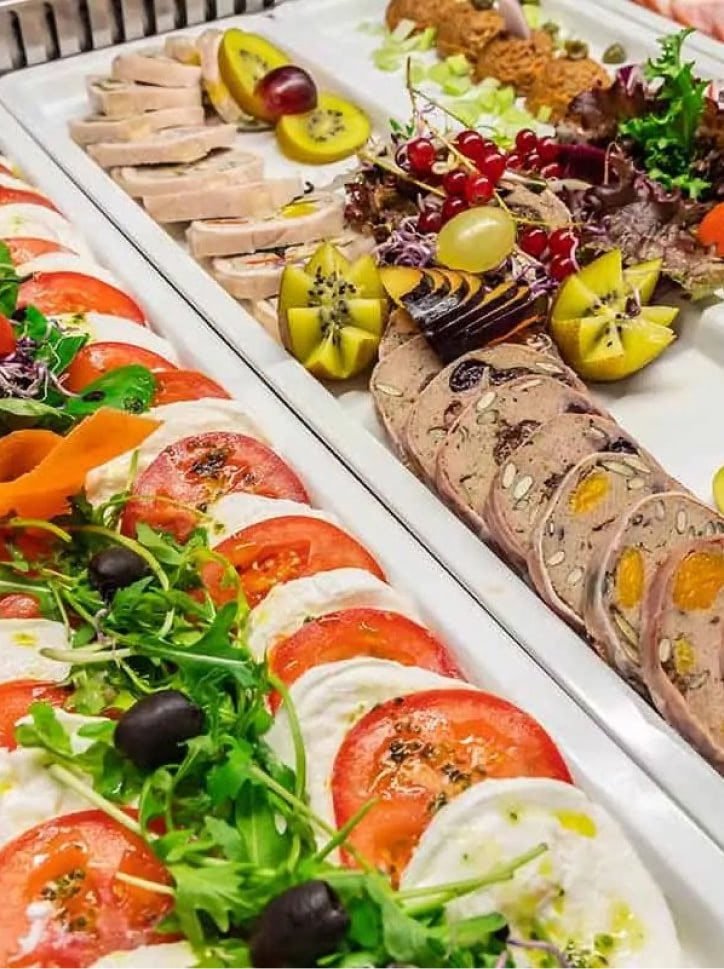 Buffet breakfast consists of a variety of cold cuts and salad served on white plates.