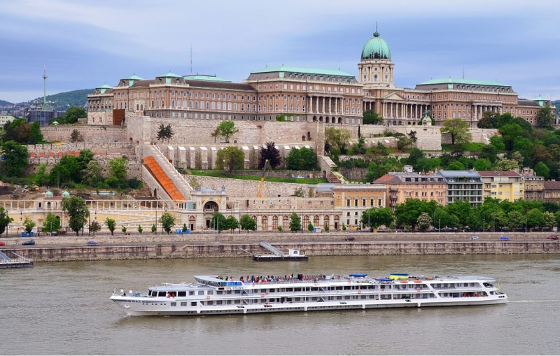 Buda Castle seen across the river Danube with a ship passing by.