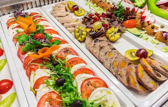 Buffet breakfast consists of a variety of cold cuts and salad served on white plates.