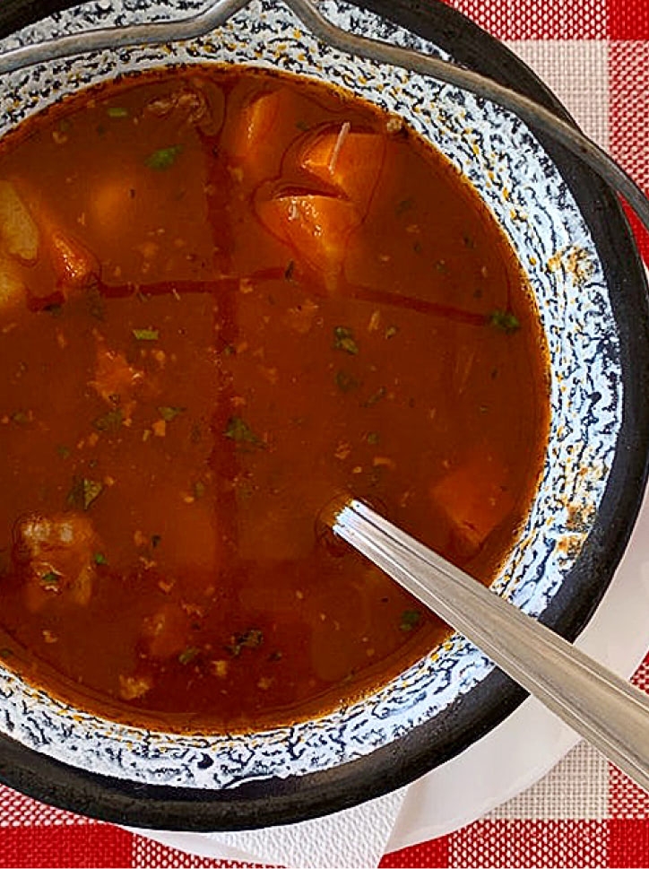 Hungarian goulash soup served in a traditional enamel pot.