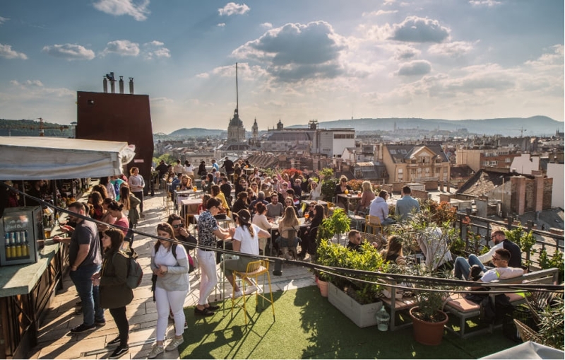 Rooftop bar busy with people on a sunny day.